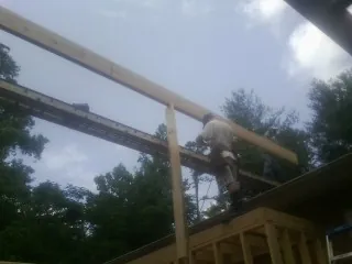 Carpenter setting a ridge beam over a new addition frame — Ice Dam Removal by Roofing Brothers in Cosmopolis