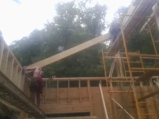 Carpenter raising a rafter beam on a new second story frame in Cosmopolis