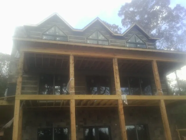 Dormers and porch framing on a large log home under construction — Roof Coating work by our crew in Cosmopolis