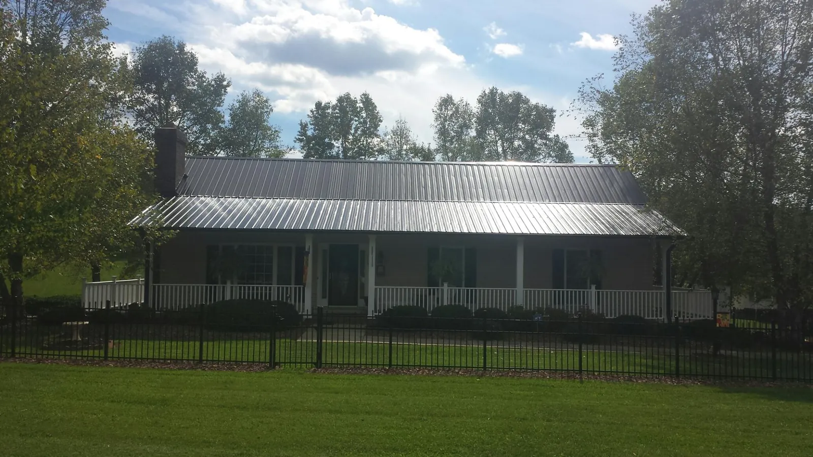 Gray metal roof on a brick ranch with a full width front porch — Gutter Guard Installation work by our crew in Cosmopolis