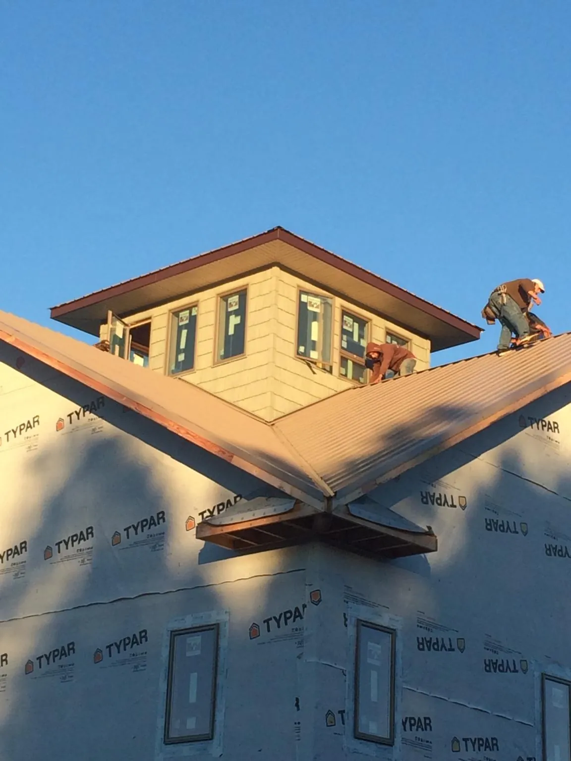 Roofers working around a rooftop cupola on a new metal roof at sunset — Roof Waterproofing in Cosmopolis by Roofing Brothers